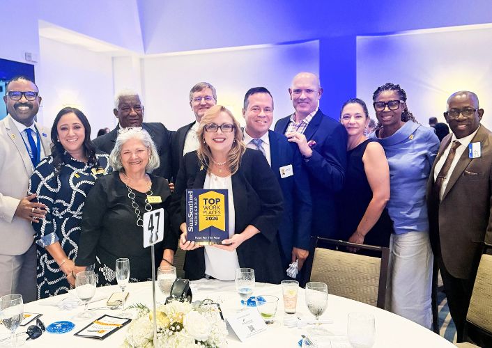 FFTP staff stand together around a table, holding Top Workplaces award