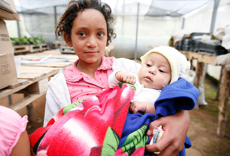 A child holding a baby in her arms.