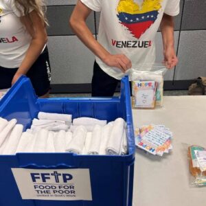 two volunteers wearing Venezuela shirts pack hygiene kits for Venezuela at FFTP headquarters