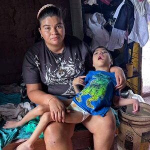 A mother holds her disabled son on her lap, Nativity Catholic Church donates a new home for her family