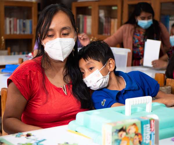A mother and her young son sit at a table at an education center in Guatemala
